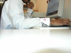 Image of a guy in a white shirt sitting by the computer, his face is not visible, only part of his chin can be seen